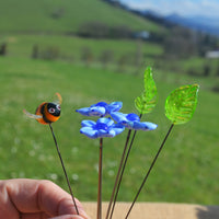 Petite composition tenue à la main d'une abeille, trois loreas bleues et deux feuilles en verre de Murano